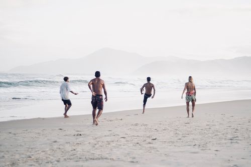 Free A group of adults playing soccer on a sandy beach with mountains in the background. Stock Photo