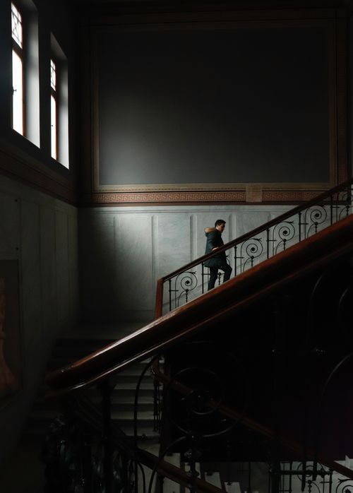 Free Silhouetted man walking up a luxurious stairway with minimalist interior design. Stock Photo