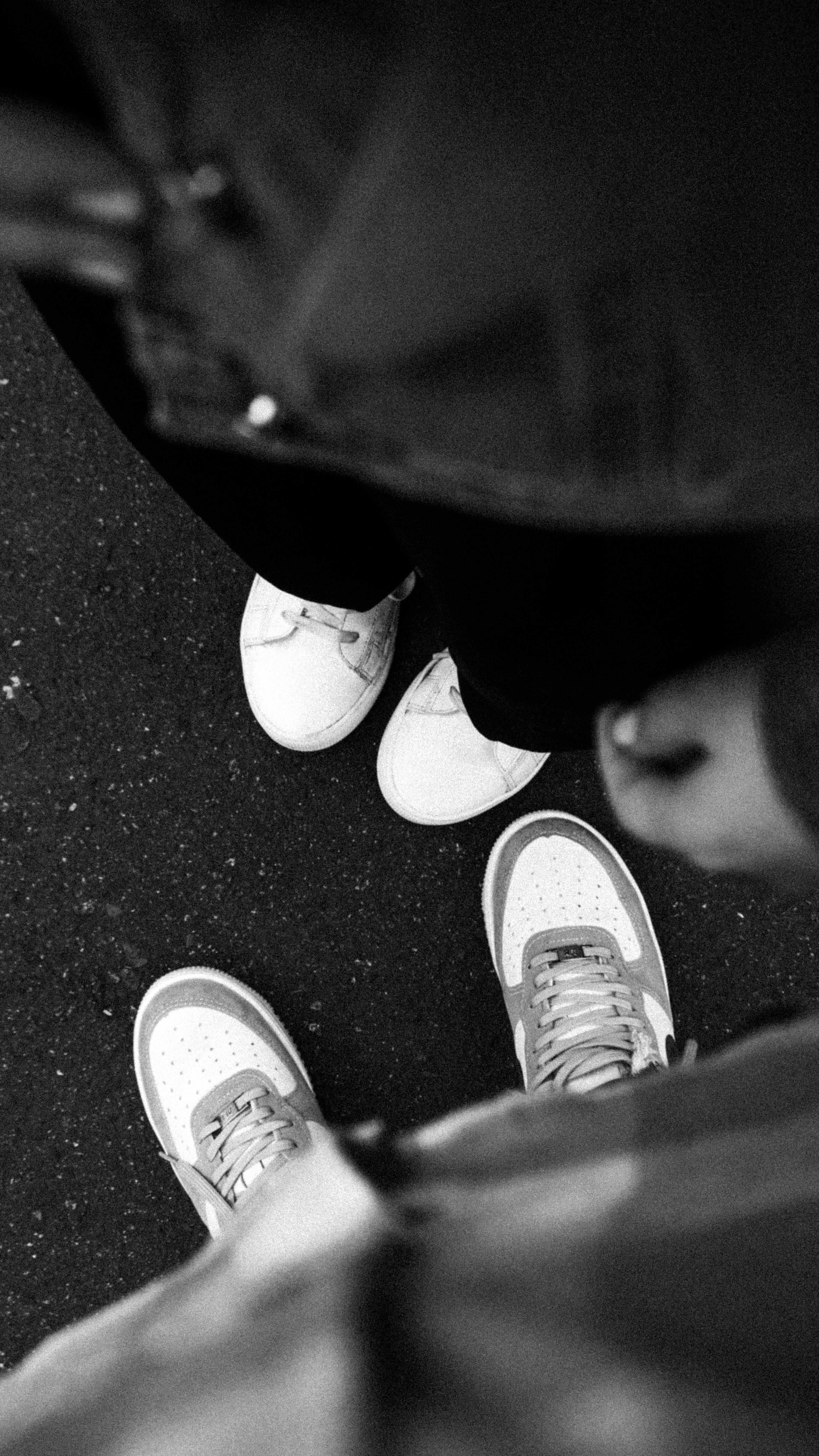 Artistic top view in black and white of two pairs of sneakers on an urban pavement.