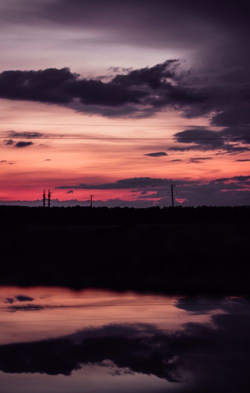 Free Vibrant sunset with dramatic clouds and water reflection, creating a mesmerizing silhouette effect. Stock Photo