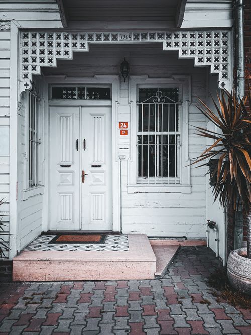 Free Classic white entrance of a mansion with ornate architectural details and plants. Stock Photo