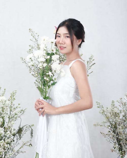 Bride in Wedding Dress Posing with White Flowers