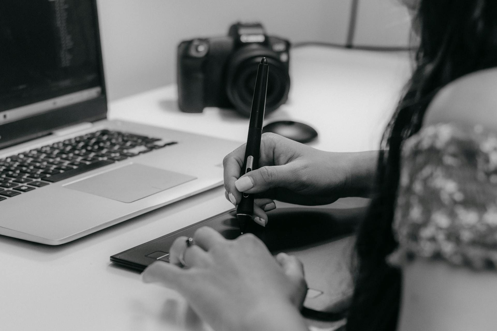 A designer working with a pen tablet and laptop, emphasizing modern digital creativity.