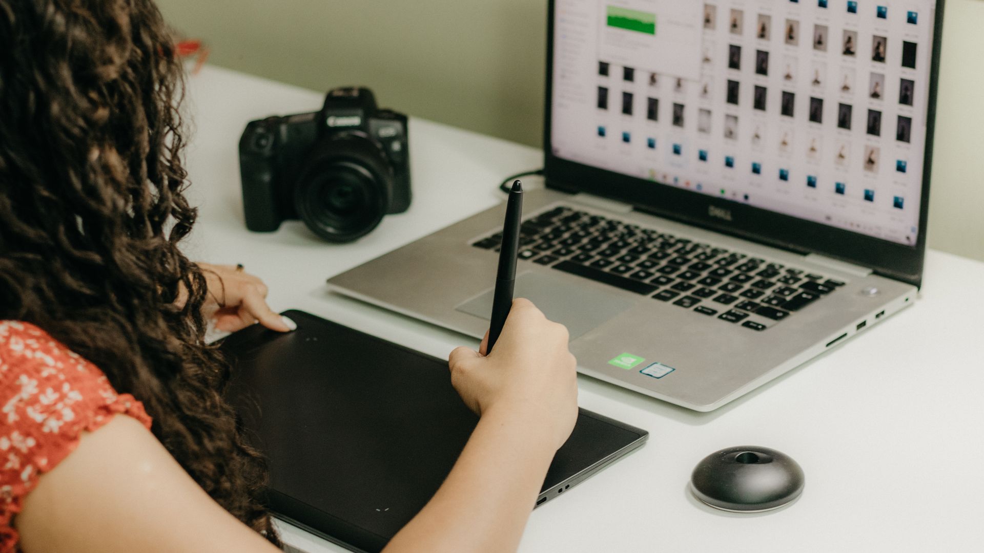 Artivigil Review: Unlocking Brain Power A woman using a graphics tablet and laptop, reviewing photos. Ideal for creative workspace themes.