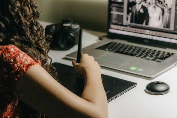 A designer editing images on a laptop with a drawing tablet — photo by Kawê Rodrigues on Pexels