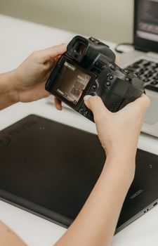 Close-up of hands holding a DSLR camera beside a digital editing tablet, ideal for photography and technology concepts.