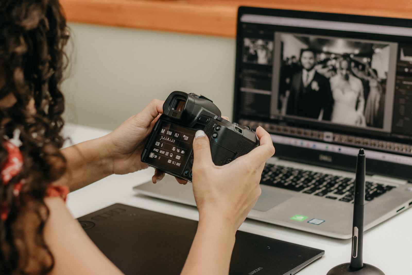 A photographer reviewing camera settings while editing photos on a laptop