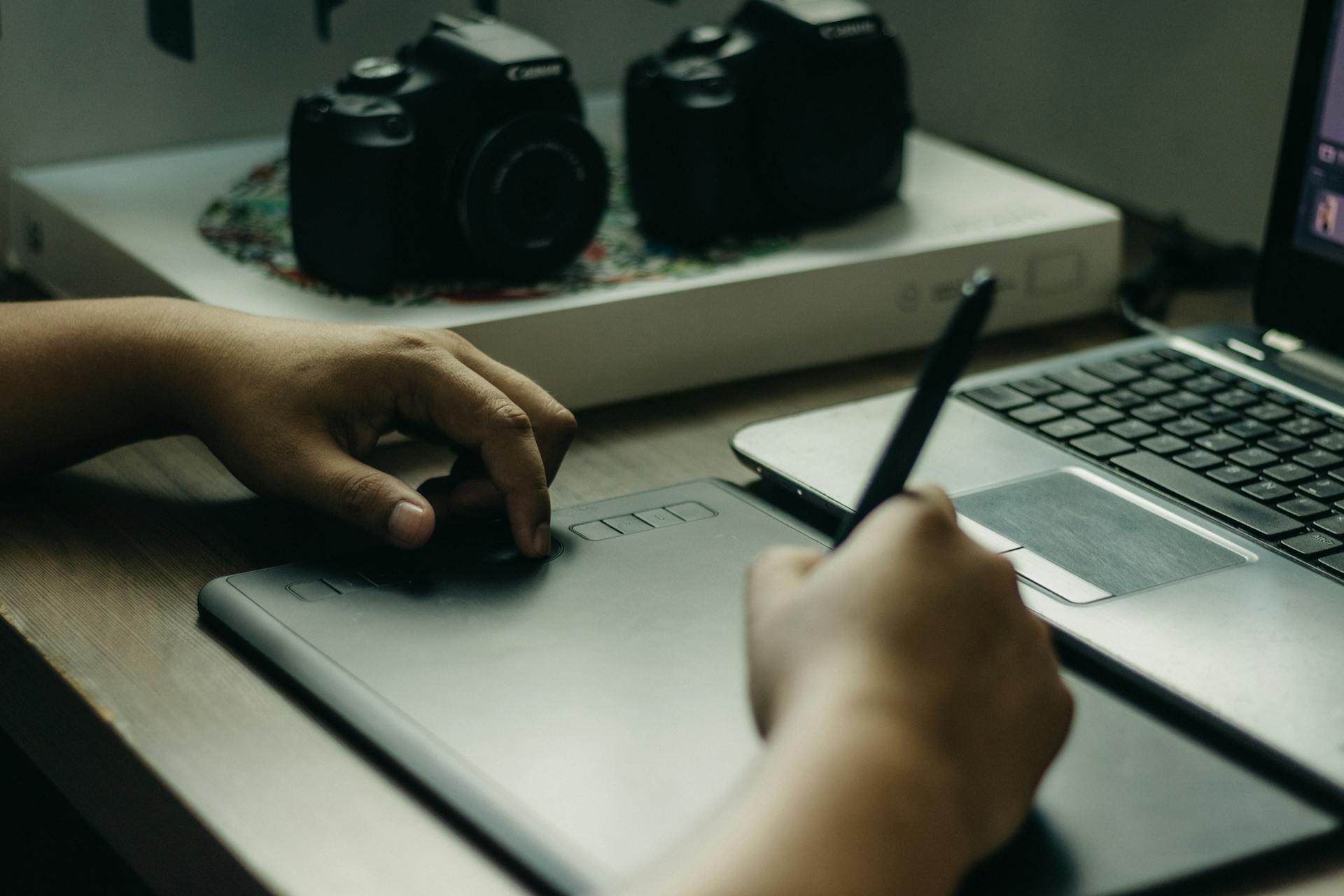 A cozy setup featuring a graphic tablet, pen, and laptop for digital art creation.