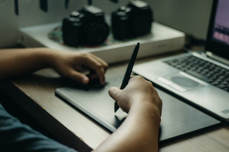 Person Drawing On Tablet Screen On Desk