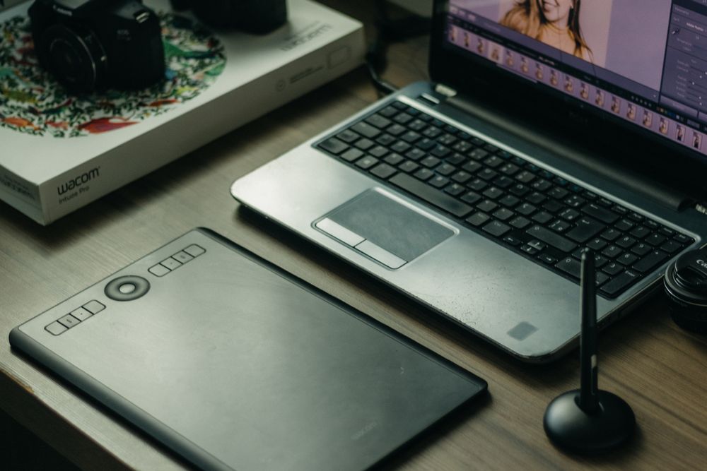 ノートパソコンとペンタブレット、スタイラスが並んだクリエイティブな作業環境