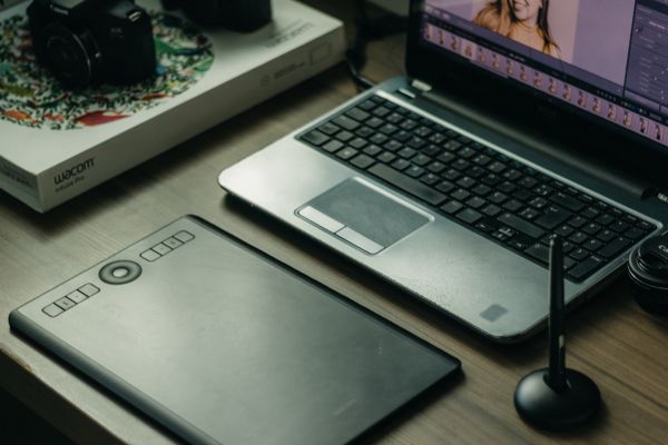 A digital artist’s desk with laptop, drawing tablet and stylus — photo by Kawê Rodrigues on Pexels