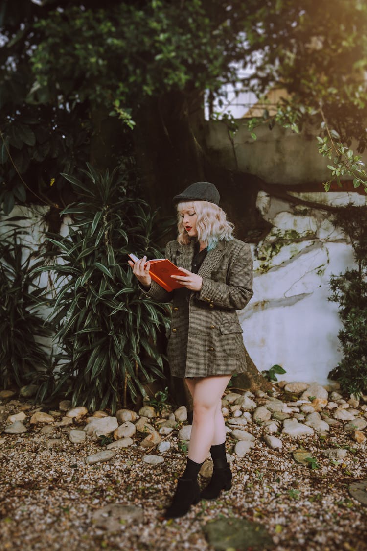 Blonde Woman Reading A Book In The Garden