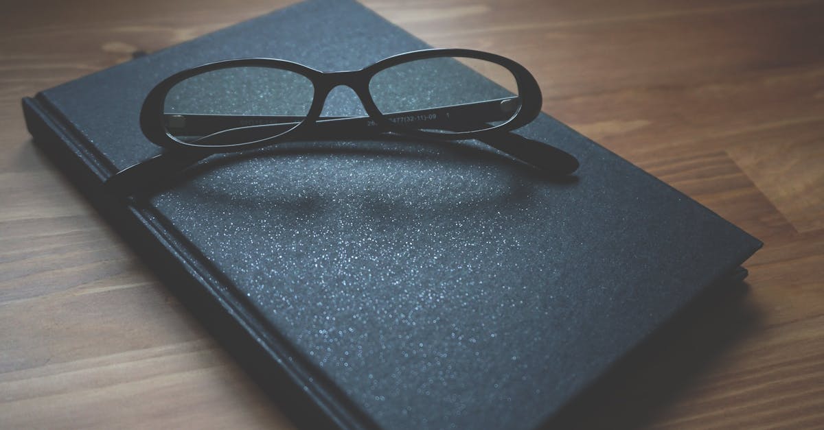Black notebook with eyeglasses on a wooden surface, capturing a professional and classic vibe.