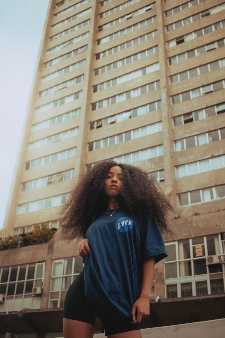 Woman In Oversized Shirt Standing Under Skyscrapers