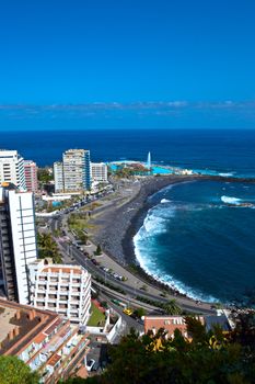 Aerial view of Puerto de la Cruz coastline with city buildings and ocean horizon.
