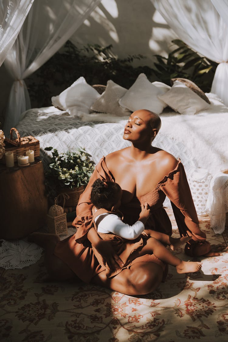 Mother Breastfeeding A Baby Daughter On The Floor