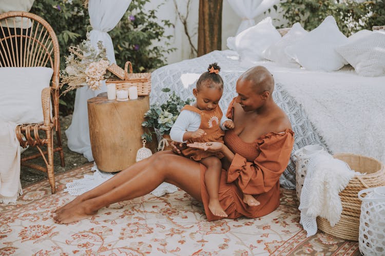 Mother And Daughter Sitting Together On A Bedroom Rug