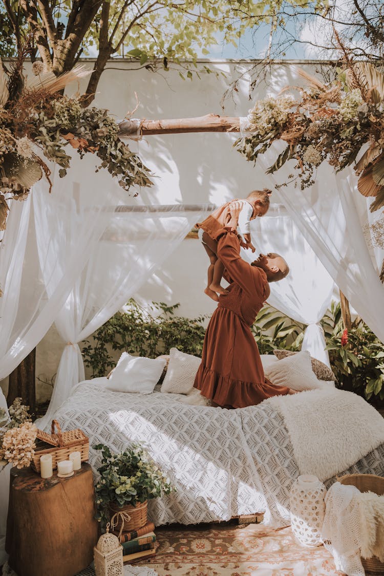 Woman With Child Playing With Child On Bed In Garden