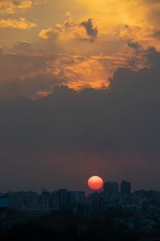 A breathtaking view of the sunset over an urban skyline in India, with dramatic clouds enhancing the scene.