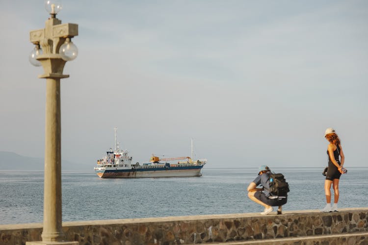 People On Boardwalk Looking At Ferry In Sea