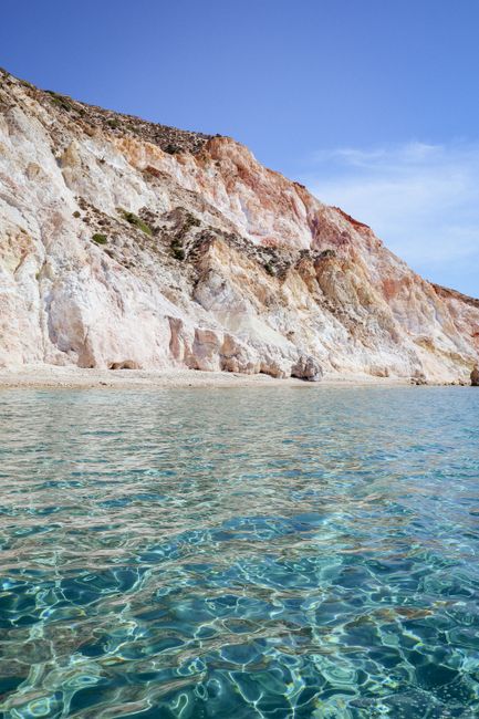 Discover stunning cliffs descending into crystal-clear turquoise waters on a sunny day.