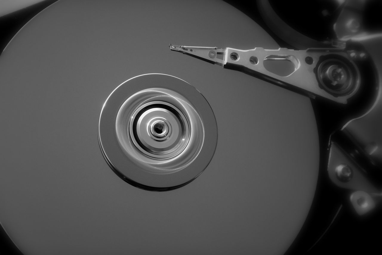 Detailed black and white close-up of an open hard drive, showcasing its mechanical components.