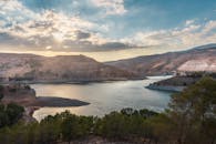 在多云的天空下，一座被山脉和树木环绕的水库景色优美