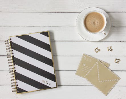 把条纹笔记本、咖啡杯和信封放在木桌上