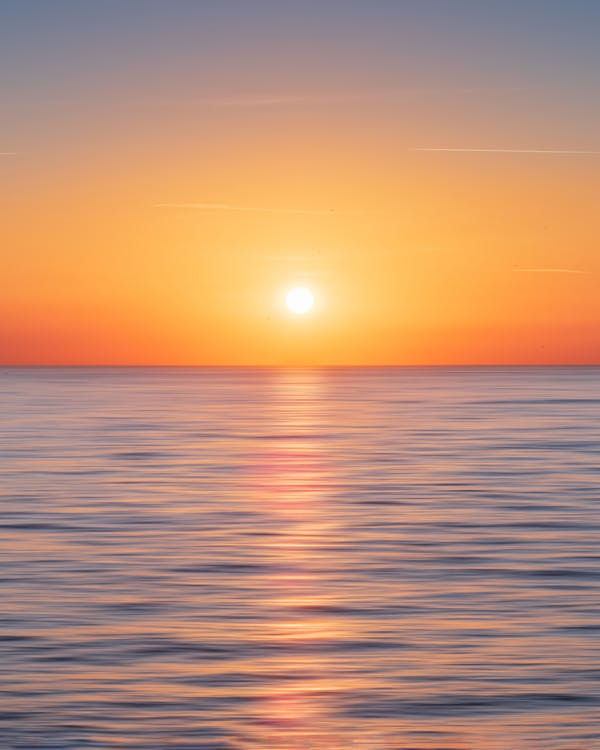 Free Calm Water With Sun and Orange Sky Stock Photo