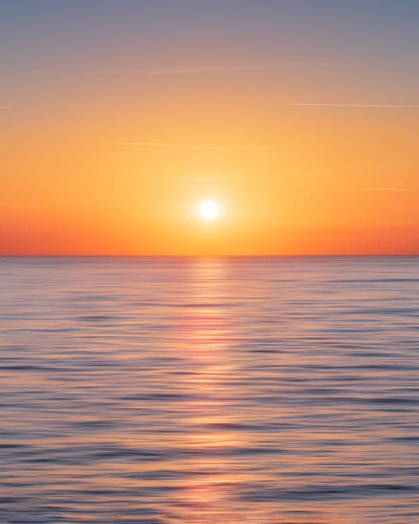 Calm Water With Sun and Orange Sky