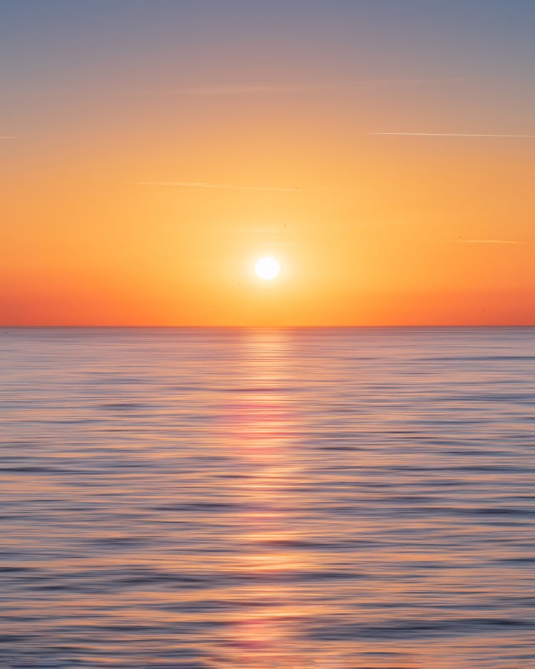 Calm Water With Sun And Orange Sky