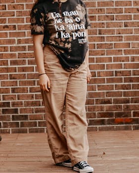 Woman posing in casual wear against a brick wall, showcasing urban fashion.