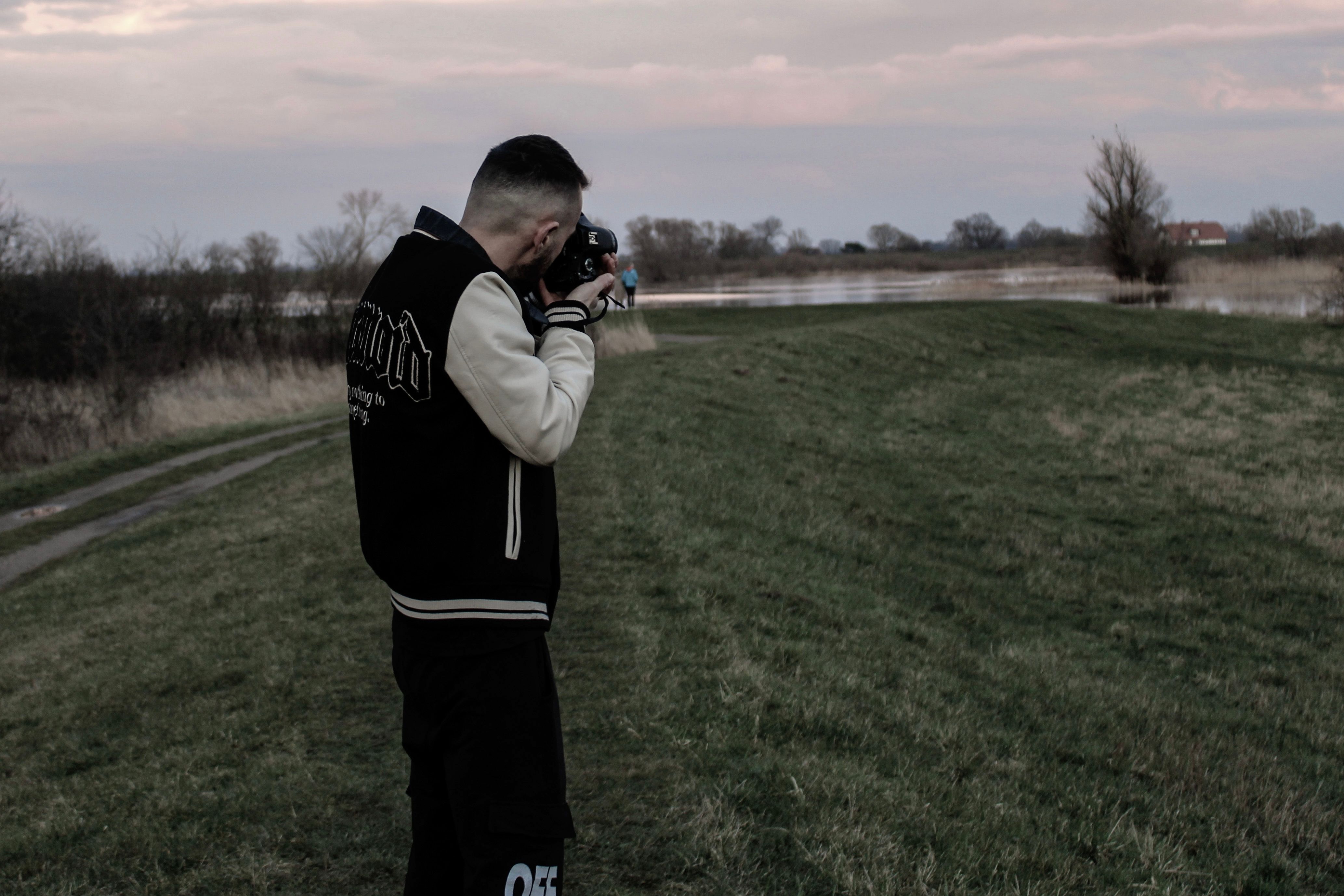 A photographer focuses on a serene field landscape in Bleckede, Germany during sunset.