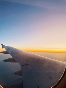 Scenic view of an airplane wing from a window seat at sunset, highlighting travel and aviation.