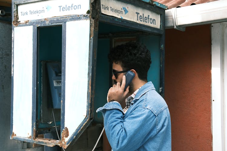 Man In Sunglasses Talking In Phone Booth