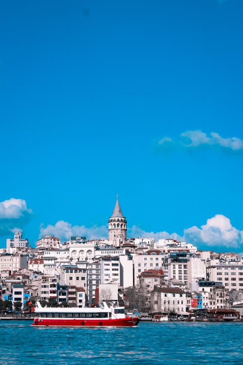 Free Scenic view of the Galata Tower and Istanbul skyline with a boat on the Bosphorus Strait under a clear blue sky. Stock Photo