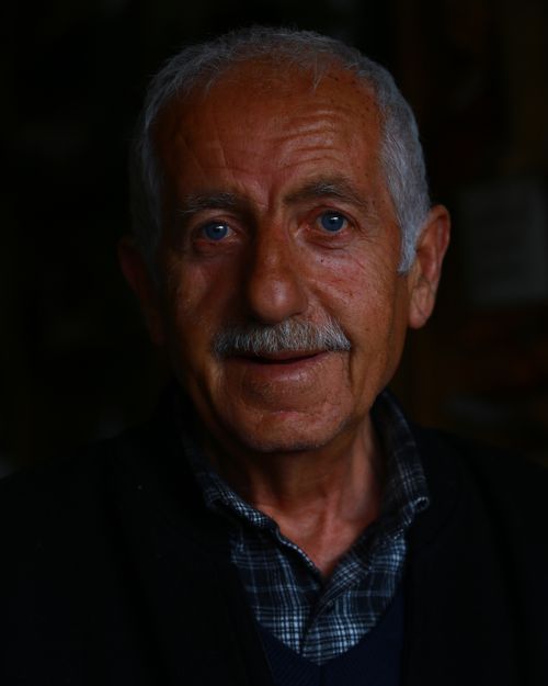 Free Studio portrait of a grey-haired elderly man with a warm smile against a black background. Stock Photo