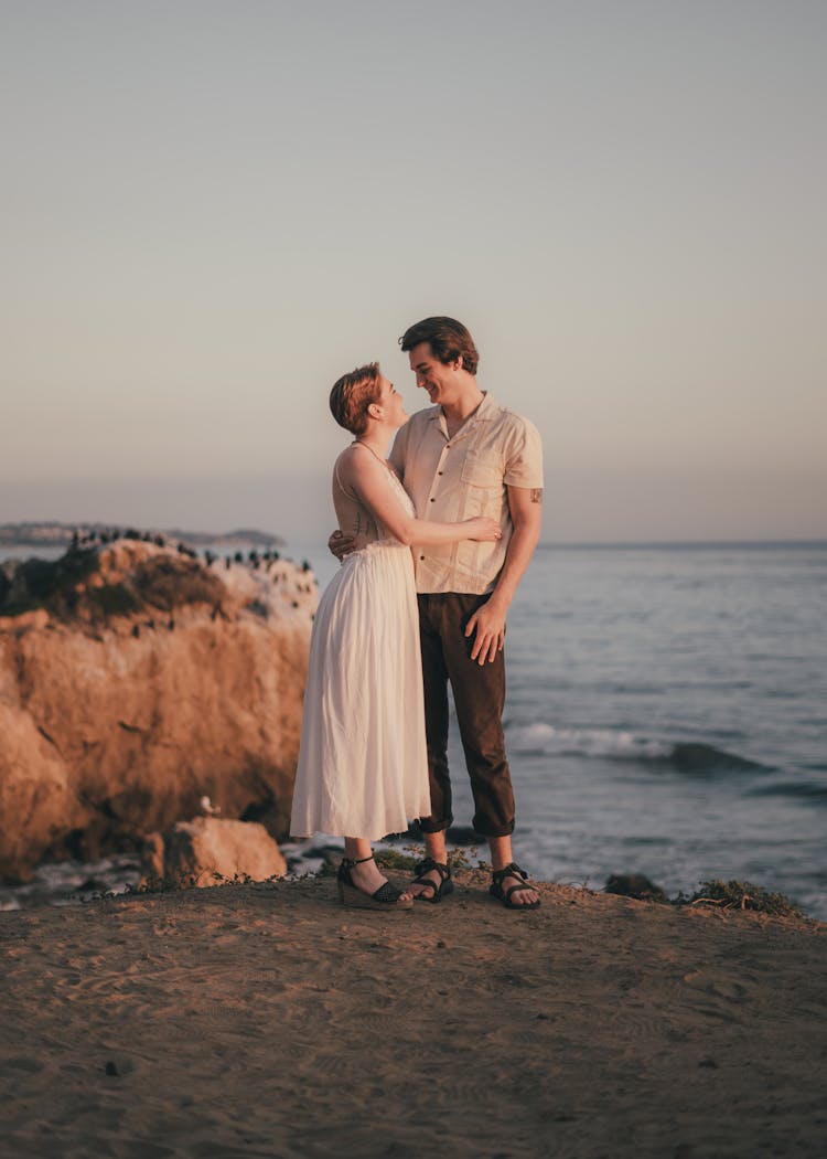 Couple Embracing On A Seaside Cliff At Sunset