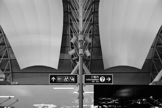 Black and white image of a modern airport interior showcasing architectural design and signage.