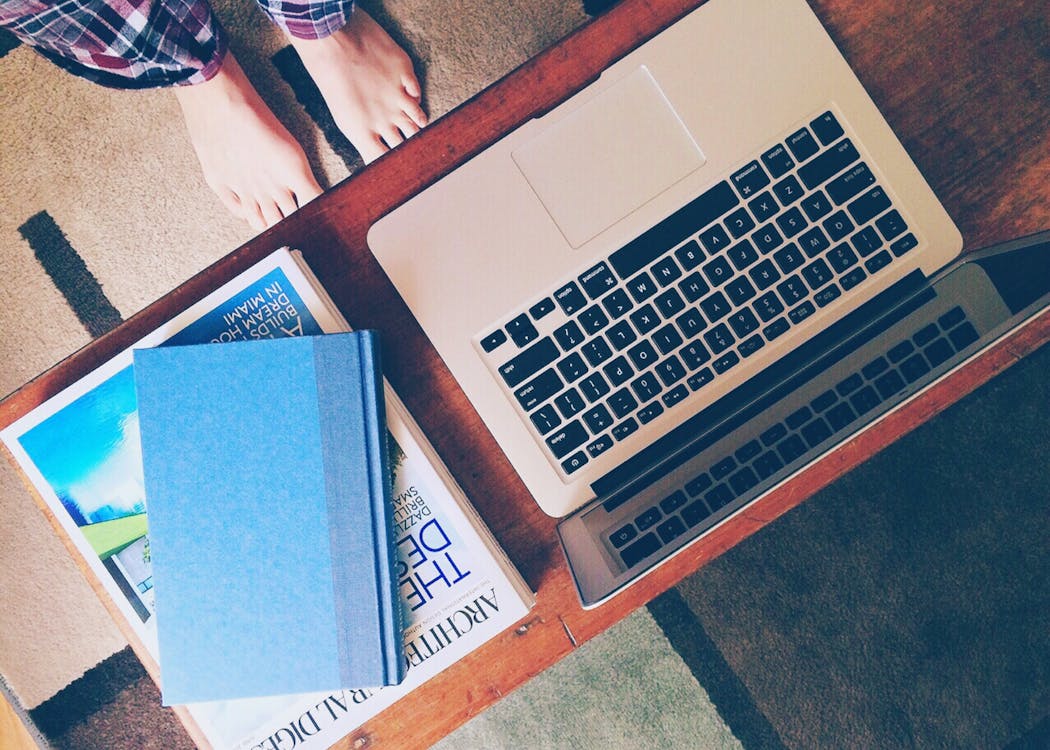бесплатная Macbook Air рядом с 2 книгами на столе Стоковое фото