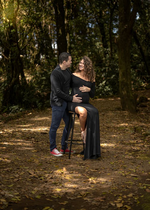 Man and Pregnant Woman in Black Dress in Forest