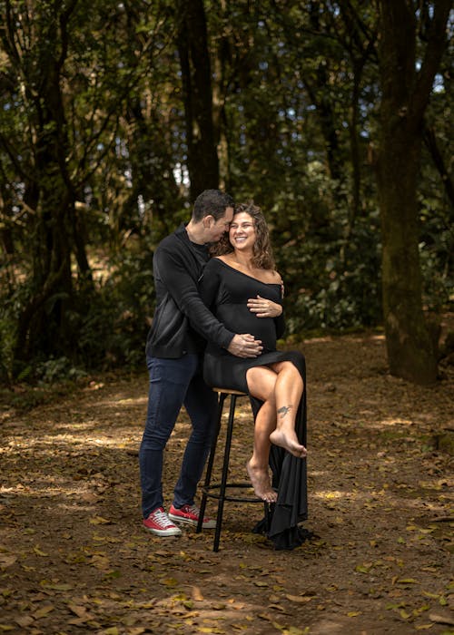 Smiling Pregnant Woman and Man in Forest