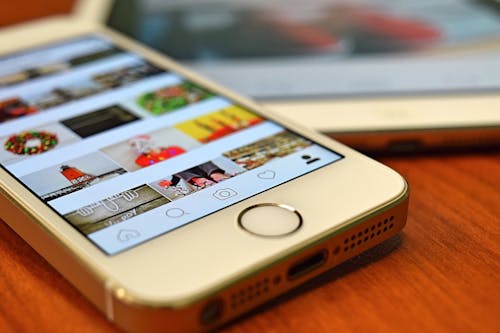 Free A close-up view of a smartphone displaying the Instagram app on a wooden surface. Stock Photo