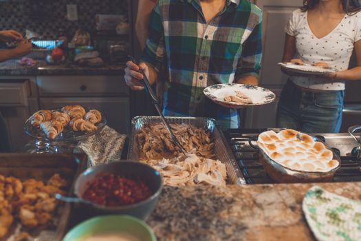 Thanksgiving feast with turkey, dinner rolls, and side dishes on a kitchen countertop.