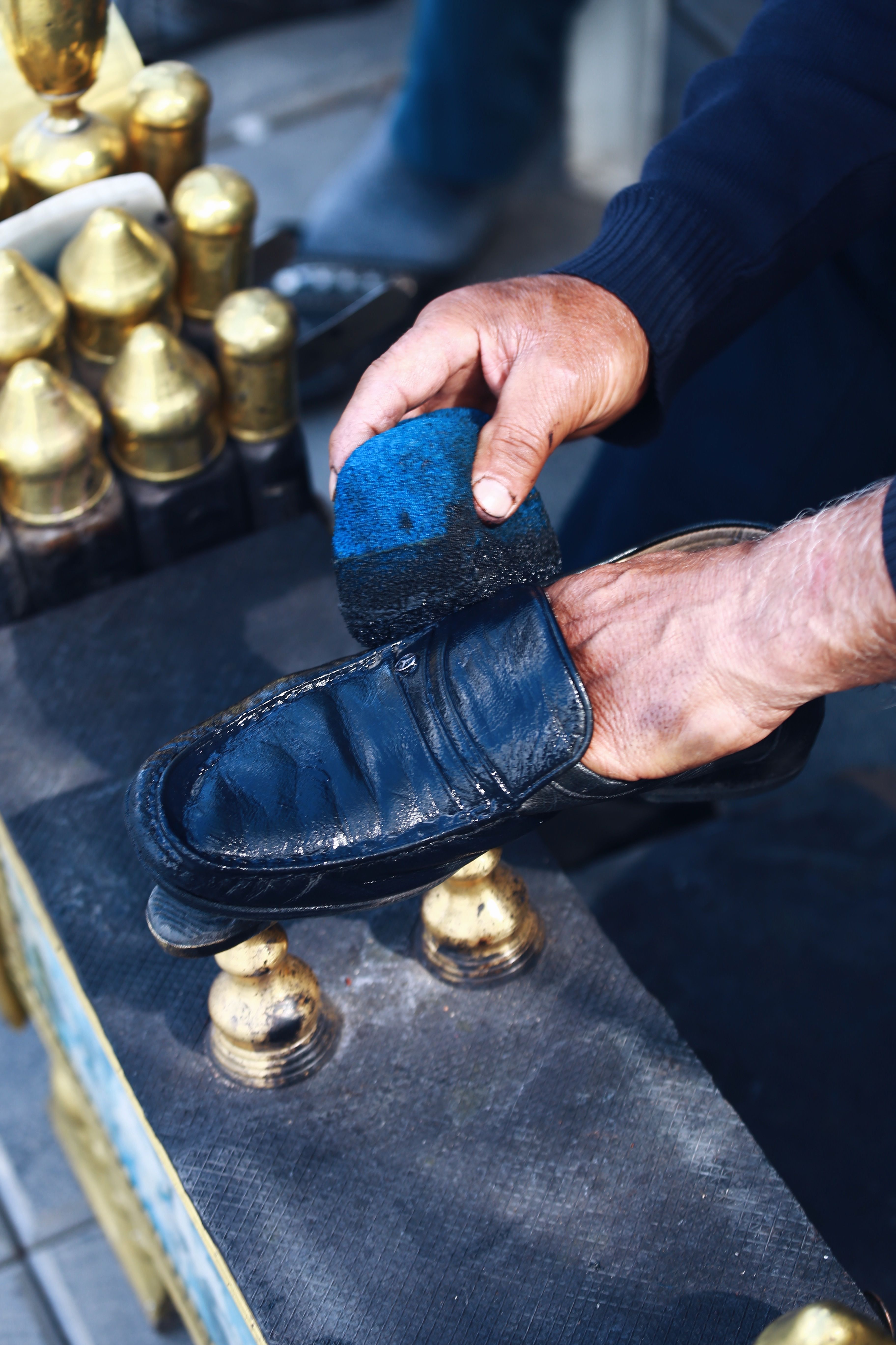 Close-up of a person polishing a leather shoe using a brush, showcasing craftsmanship and care. - How to Spot Fake vs. Original Handbags