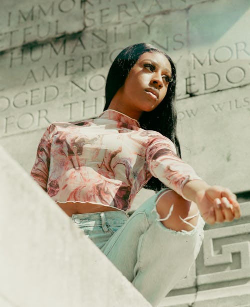 A woman sitting on a ledge with her hands on her hips