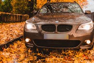 一辆豪华轿车停在五彩缤纷的秋叶中，营造出温馨迷人的氛围