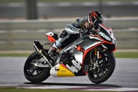 在高速比赛中，专业摩托车赛车手倾斜转弯，展示了敏捷性和精确性