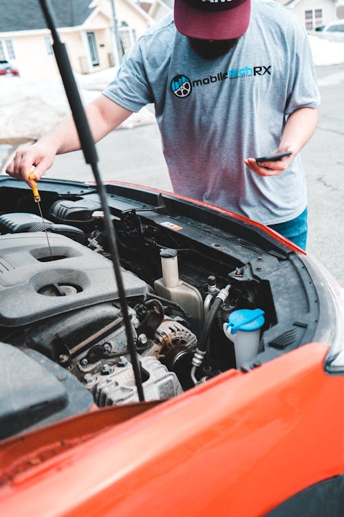 Man Standing near Car Engine with Cellphone 