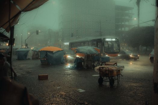 Moody night scene with city bus and street stalls in heavy rain, creating a dramatic urban atmosphere.